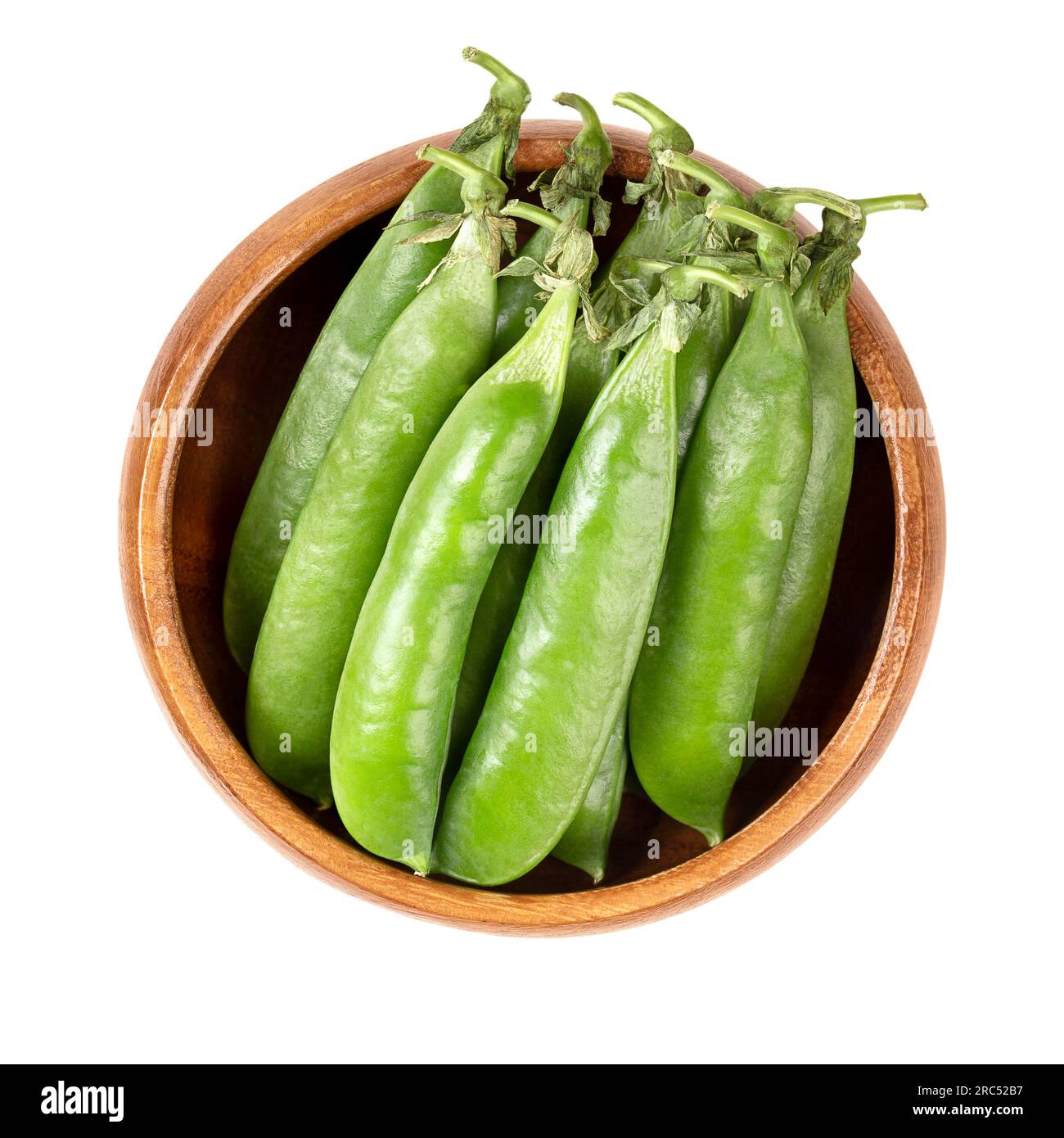 Fresh pea pods, in a wooden bowl. Bunch of pods, containing green peas, the fruits and seeds of Pisum sativum, a flowering annual plant. Stock Photo