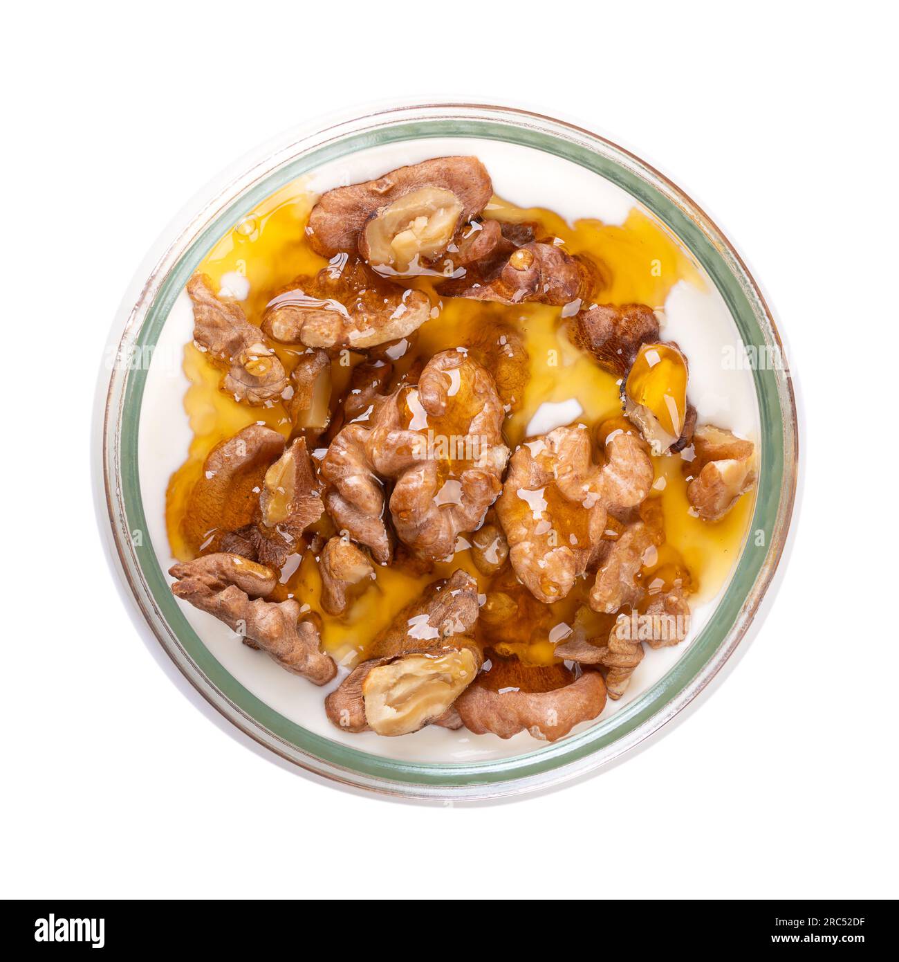 Greek yogurt with honey and roasted walnuts, in a glass jar. Yiaourti me meli, a traditional treat, dessert and snack, made of stirred, creamy yogurt. Stock Photo