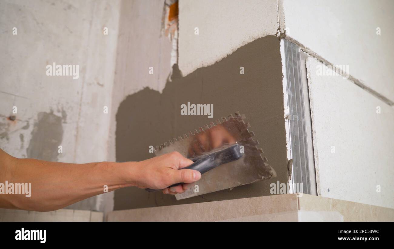 Applying an adhesive solution to a plasterboard wall for gluing ceramic tiles. The adhesive