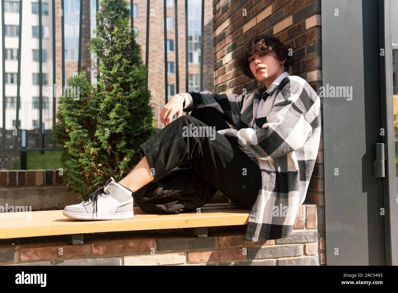 young man sits relaxed on a city bench Stock Photo