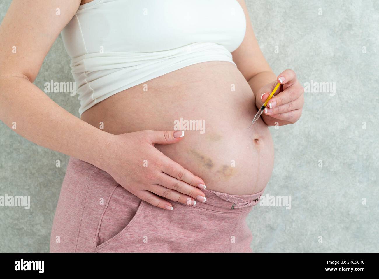 Blood thinners concept. Pregnant woman making injection in stomach with