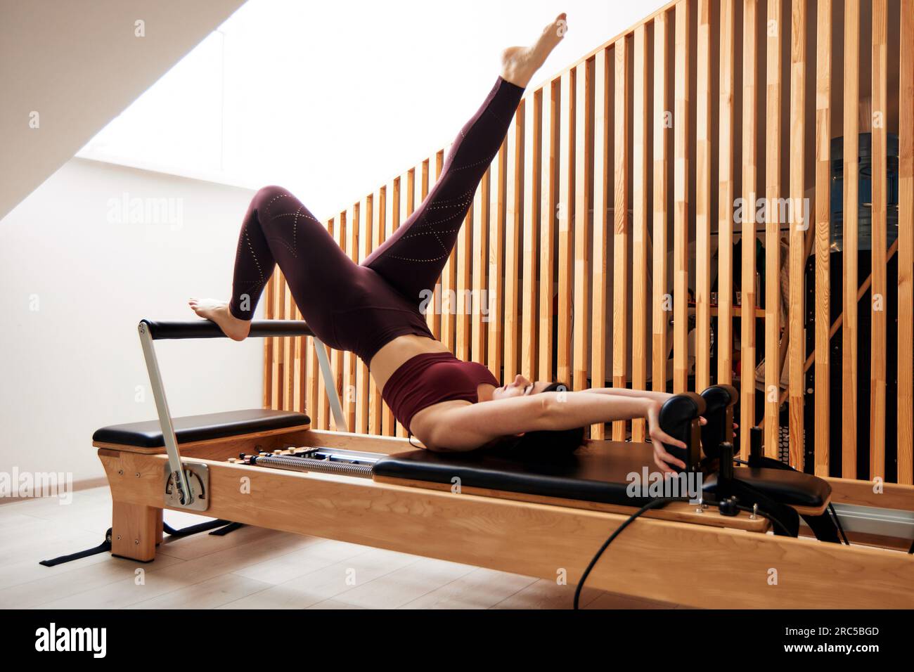 Young Girl Is Doing Pilates In A Bright Studio On A Reformer Bed ...