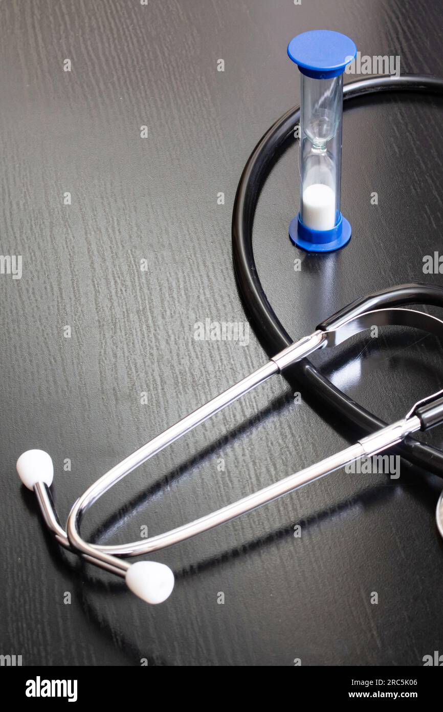 Stethoscope and hourglass on a wooden table close up Stock Photo