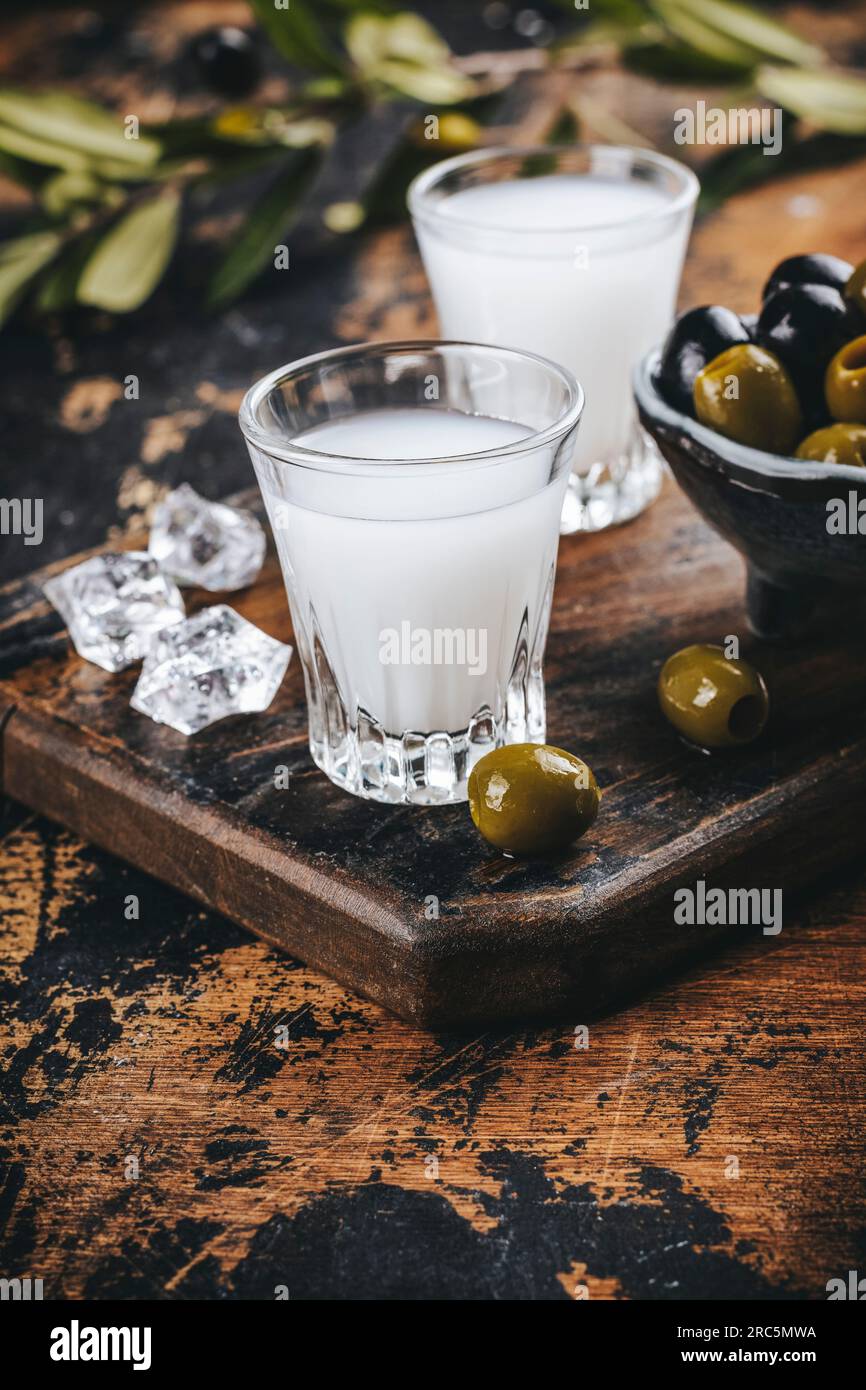 Traditional greek vodka ouzo and marinated olives on rustic wooden