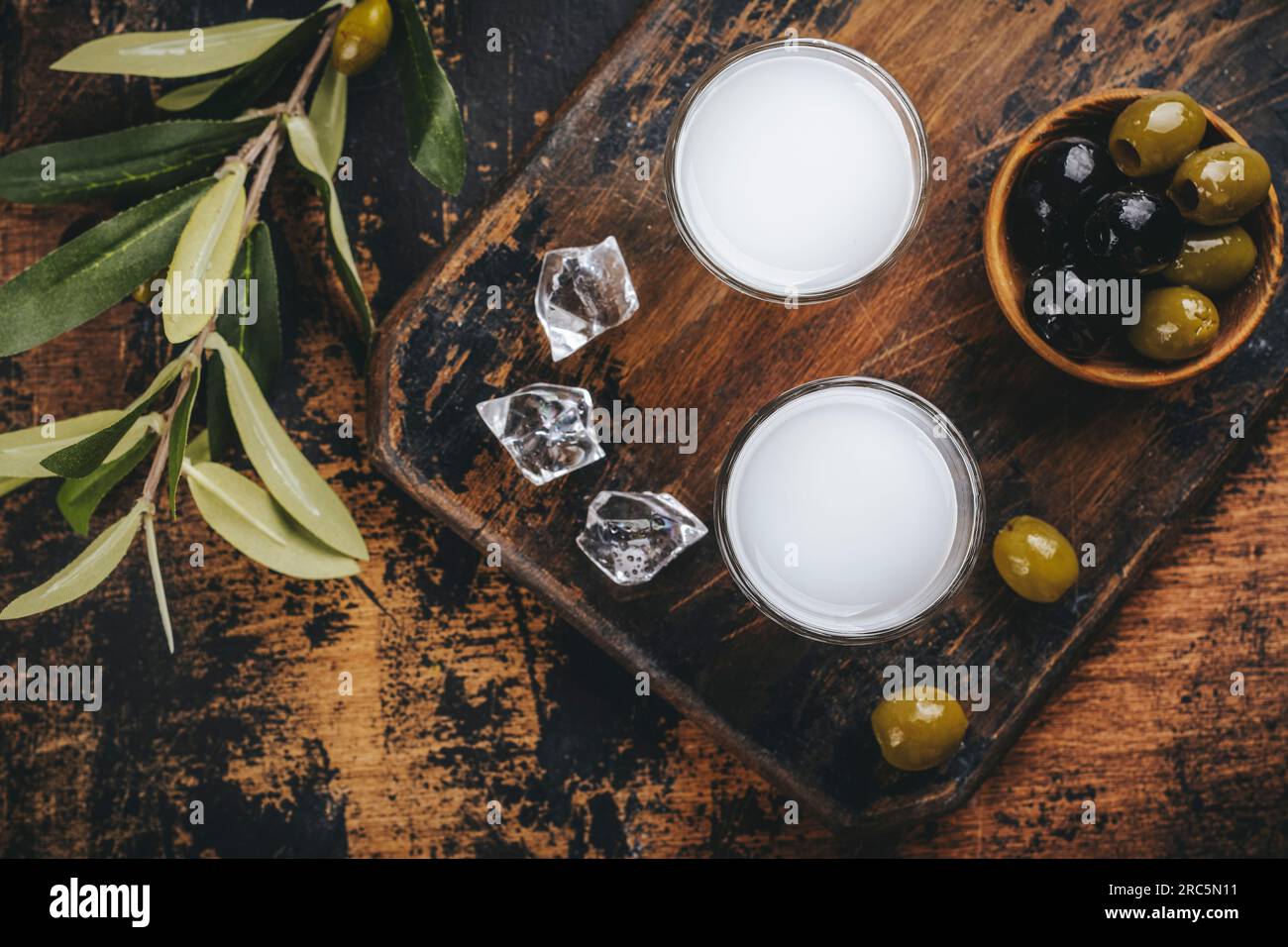 Traditional greek vodka ouzo and marinated olives on rustic wooden