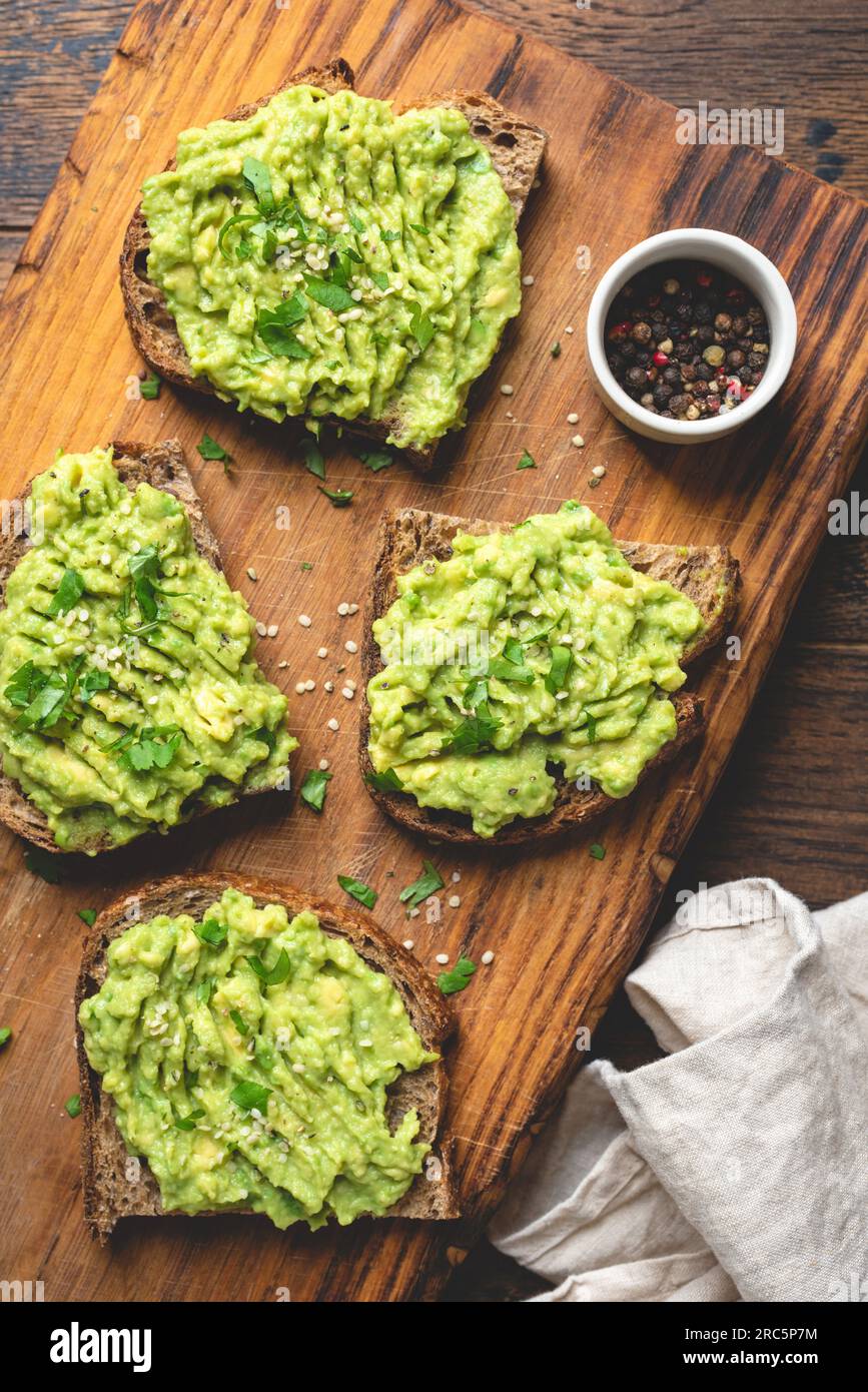 Vegan avocado and rye bread toasts with hemp seeds and chopped parsley. Healthy eating, dieting, weight loss food concept Stock Photo
