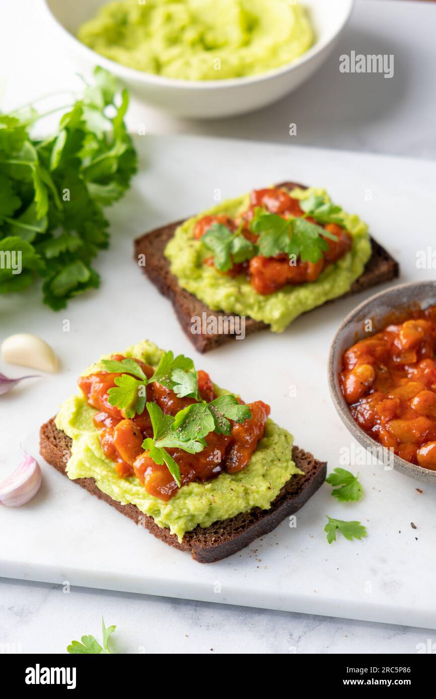 Avocado toast with mashed avocado and baked beans topping, healthy vegan protein and healthy fats packed snack or lunch Stock Photo
