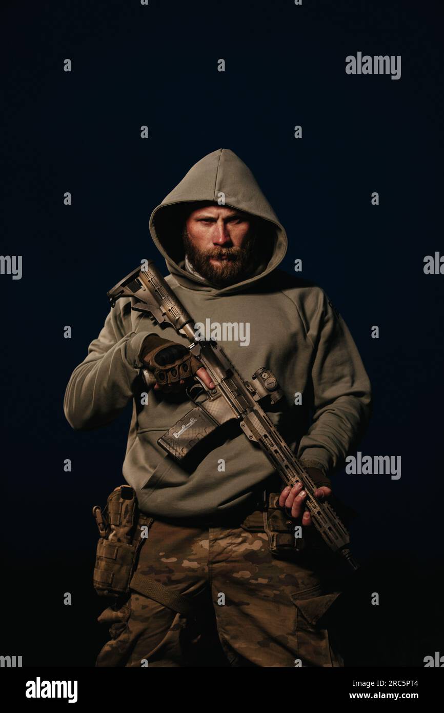 Ukrainian Soldier with his rifle wearing hoody on a black background ...