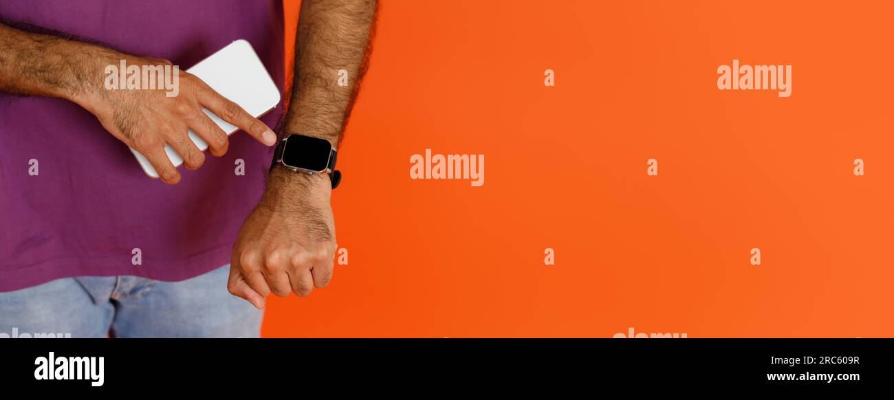 Unrecognizable dark-skinned man using application on smartphone and smart watch Stock Photo