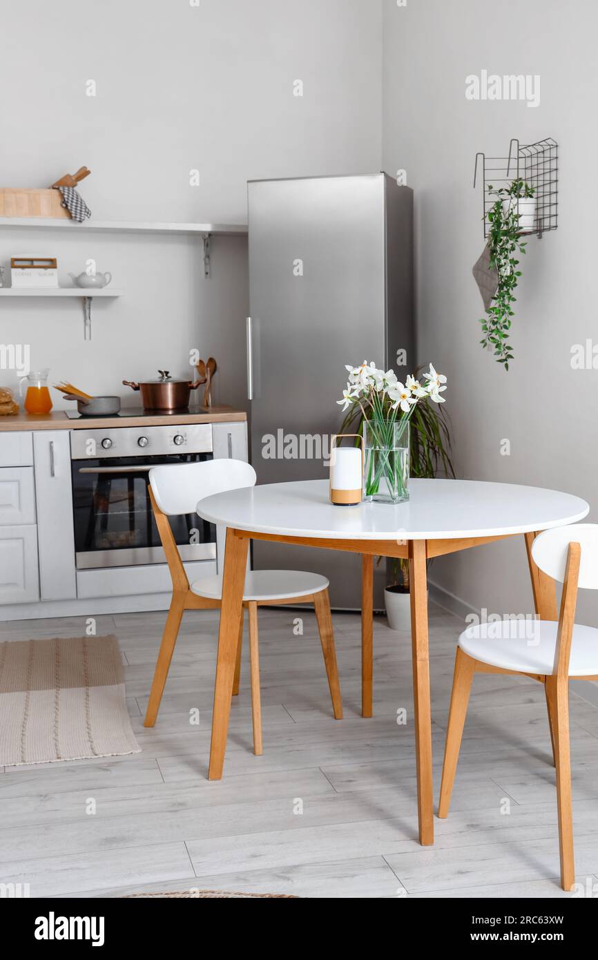 Interior of light kitchen with stylish fridge, counters, table and ...