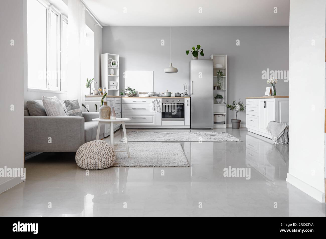 Interior of light kitchen with stylish fridge, counters, sofa and