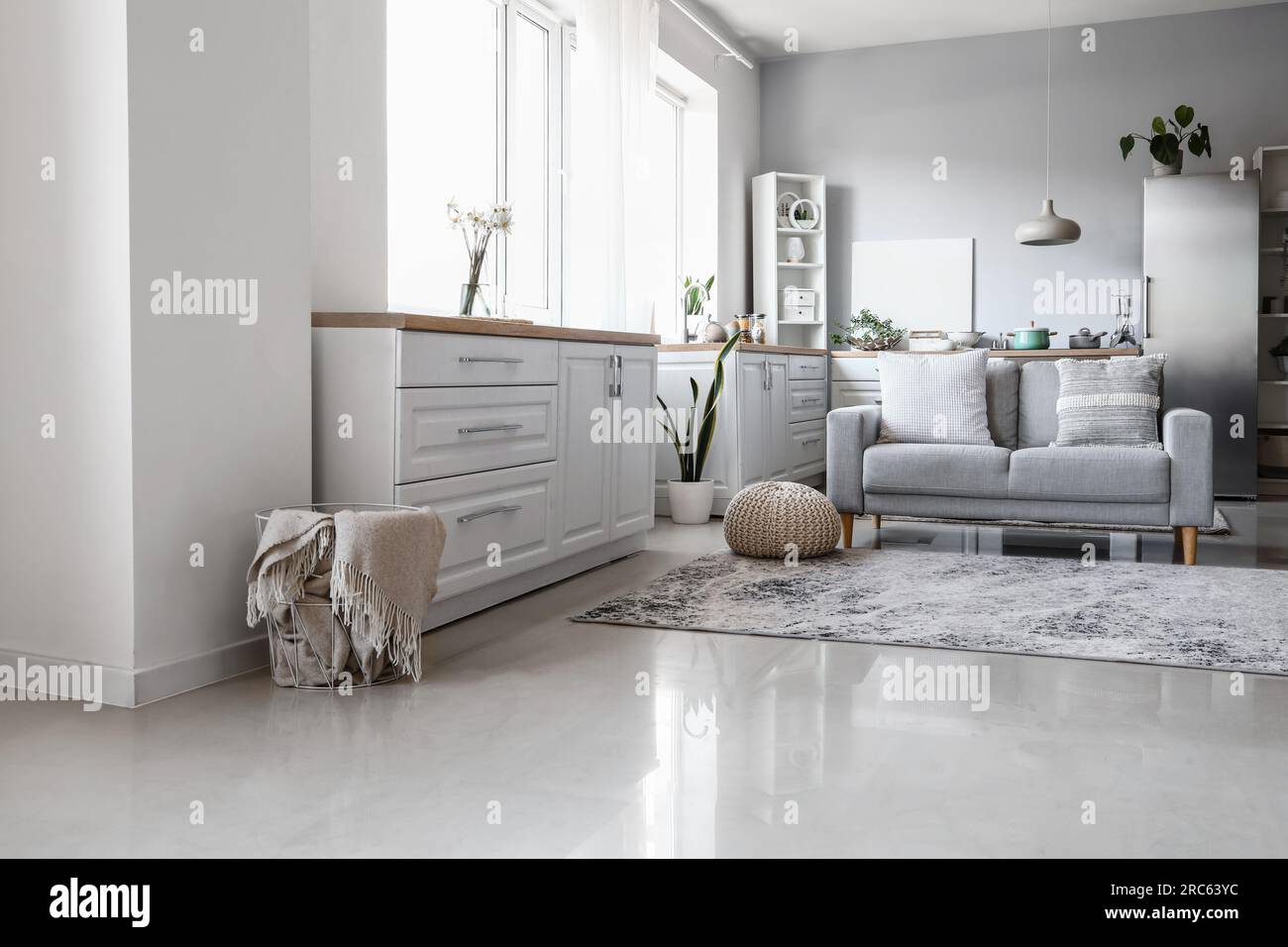 Interior of light kitchen with stylish fridge, counters, sofa and