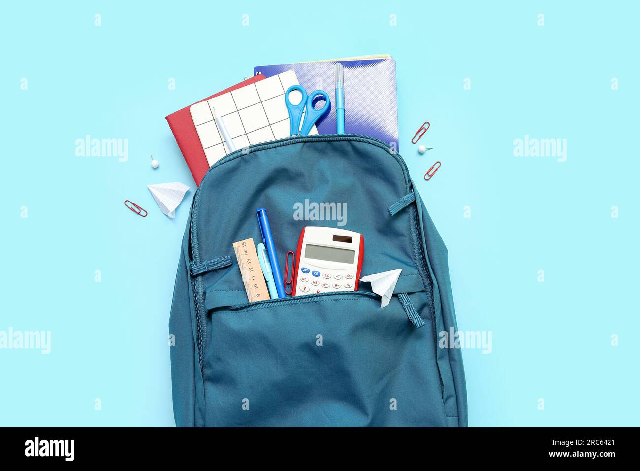 School backpack with different stationery on blue background Stock Photo