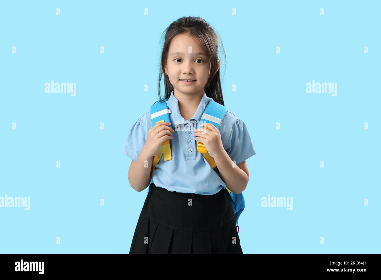 Little schoolgirl with backpack on light blue background Stock Photo ...