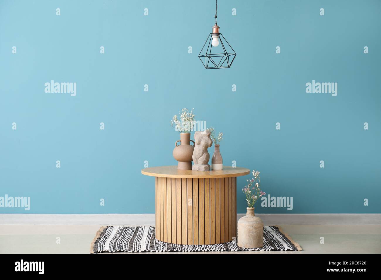 Coffee table with decor and gypsophila flowers in vases near blue wall ...