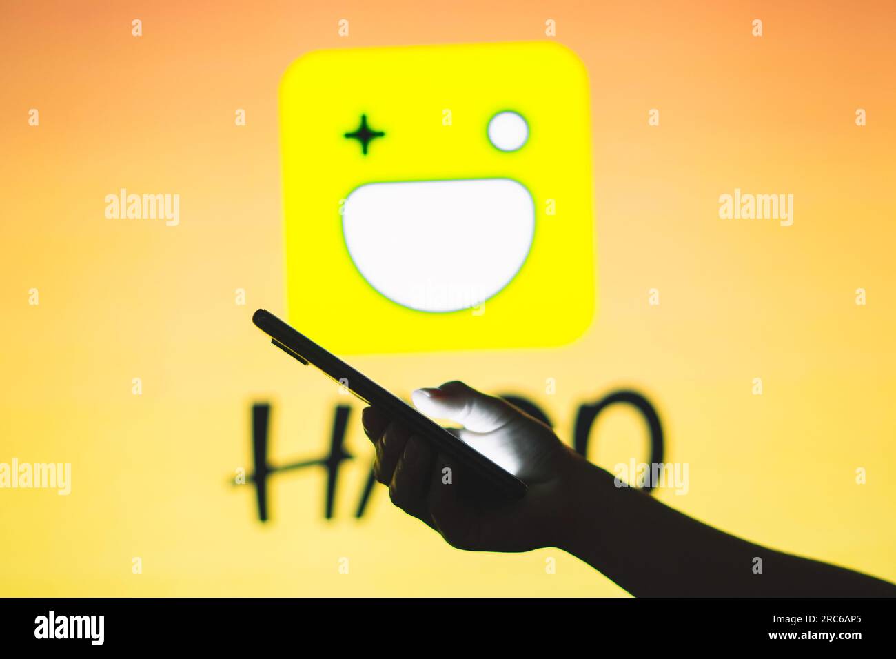 In this photo illustration, a person holds a smartphone with the Hago logo in the background. Stock Photo