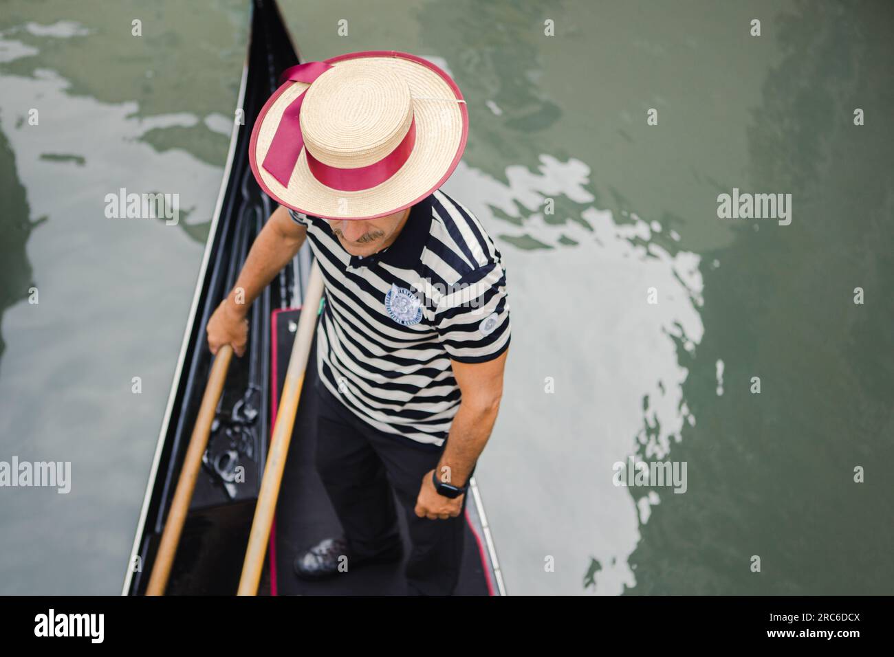 Gondolier with a gondolier hat on a gondola rowing in Venice Italy Stock Photo