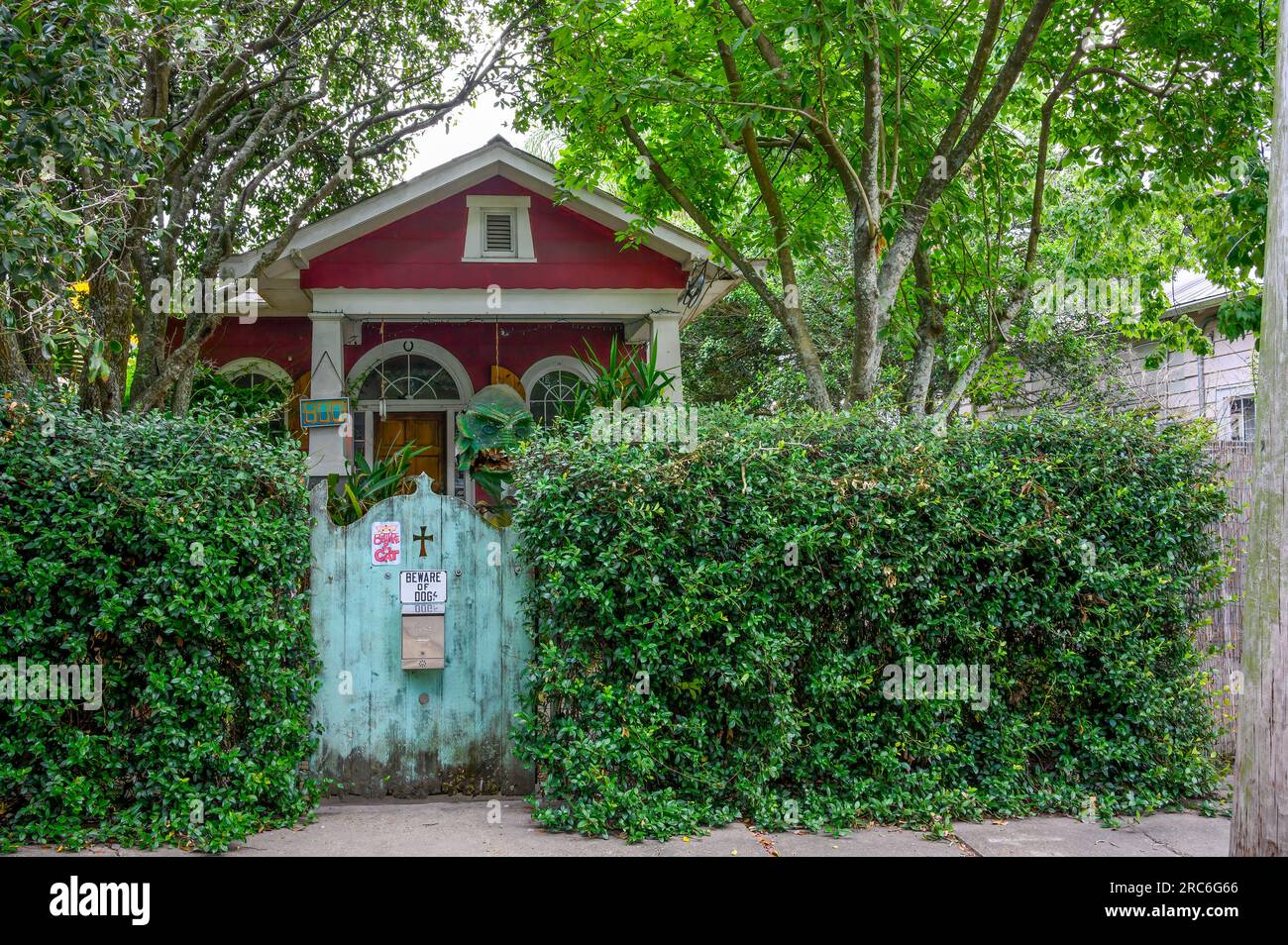 NEW ORLEANS, LA, USA - JUNE 24, 2023: Dark and spooky cottage behind a wooden gate with 'Beware of Dog' and 'Beware of Cat' signs Stock Photo