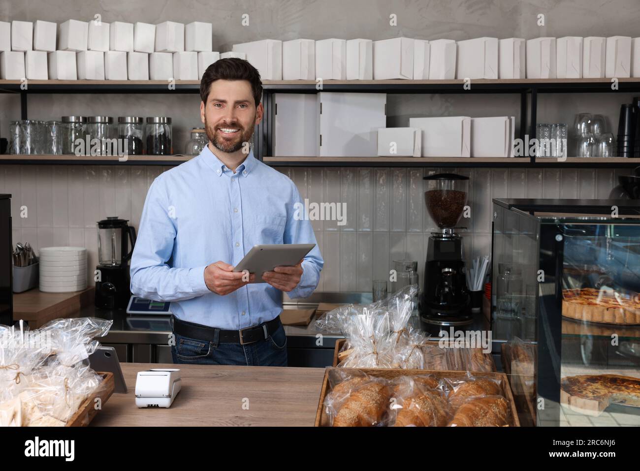 Happy business owner with tablet at cashier desk in bakery shop Stock ...