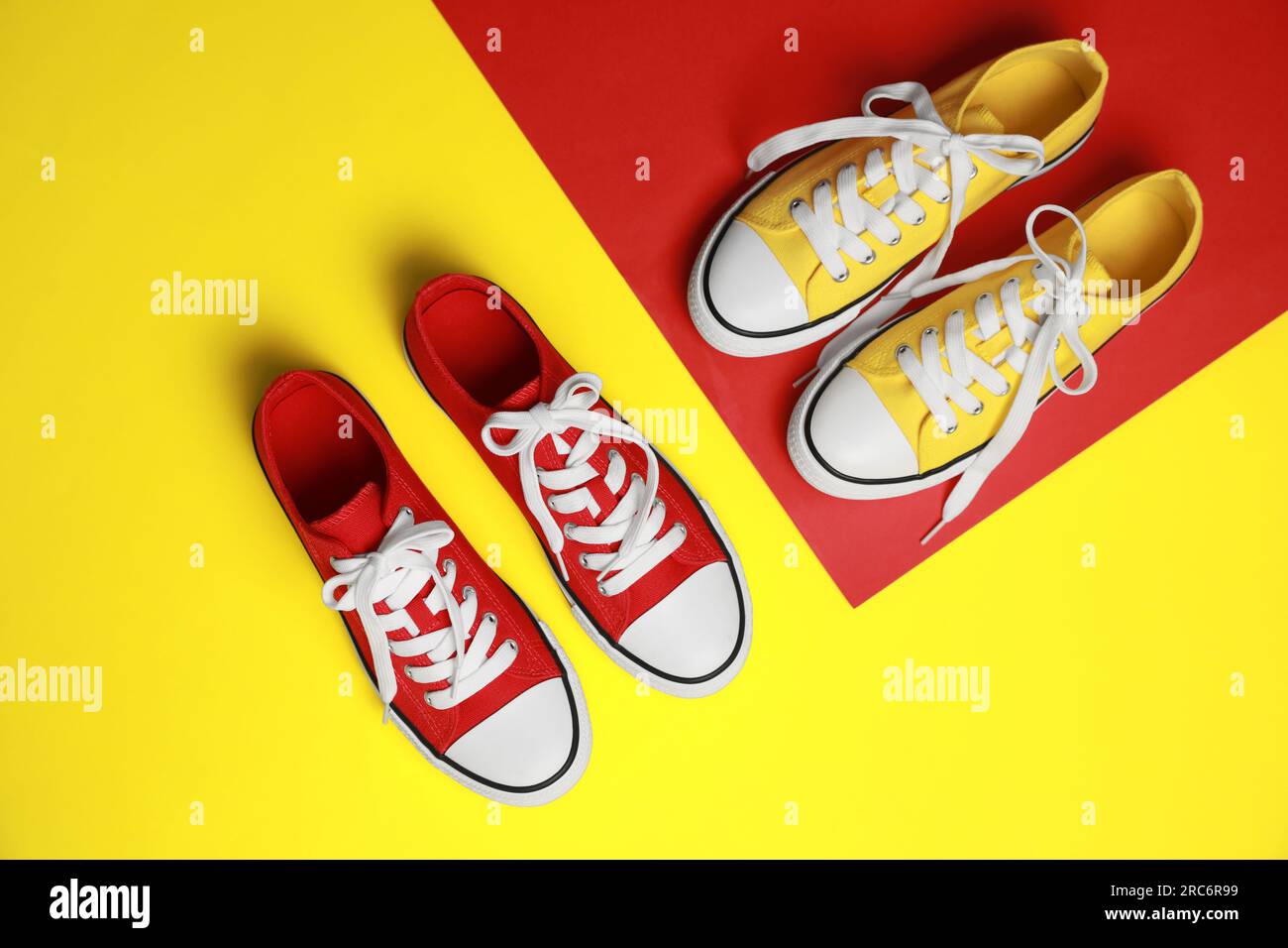 Red and yellow classic old school sneakers on color background, flat lay Stock Photo