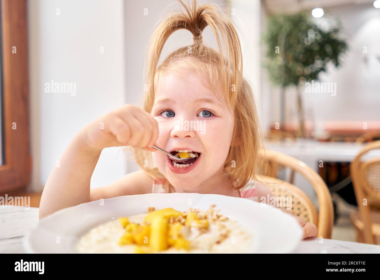 Little kid having breakfast at cafe. Adorable girl drinking still water ...