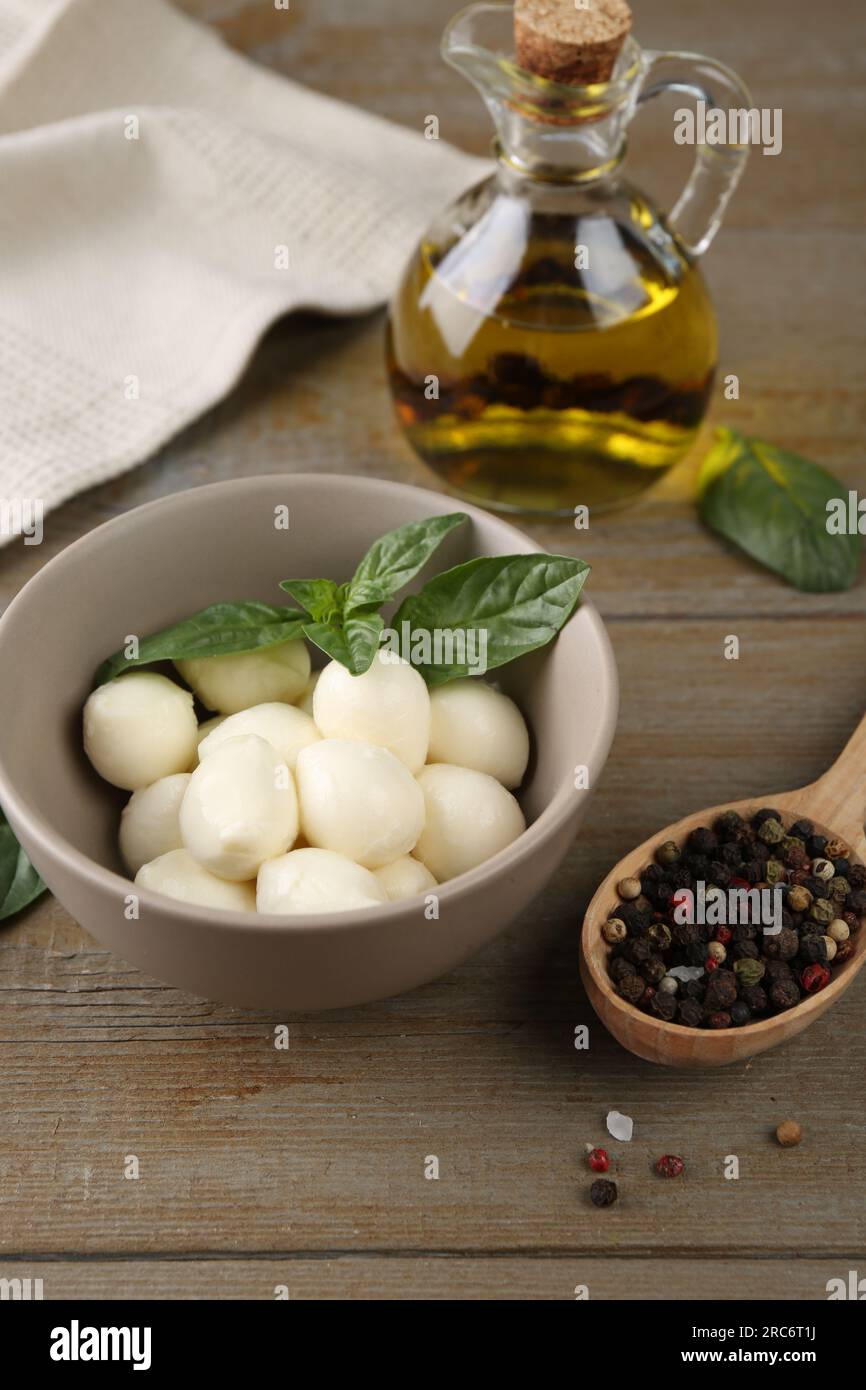 Tasty mozarella balls, basil leaves and spices on wooden table Stock Photo