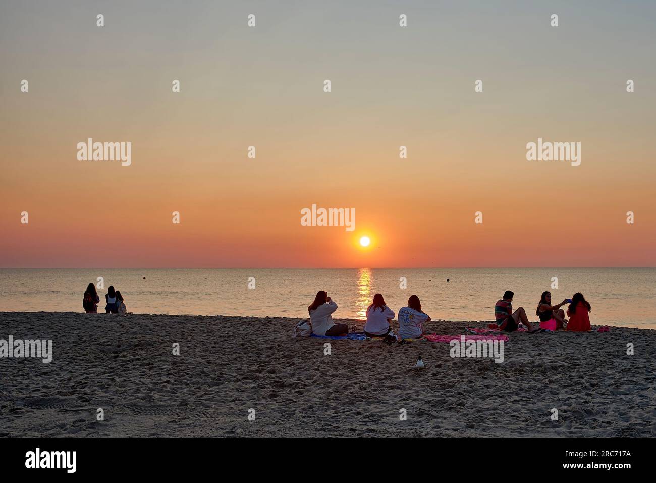 Groups of beachgoers enjoy the sunrise at Rehoboth Beach, Delaware USA. Stock Photo