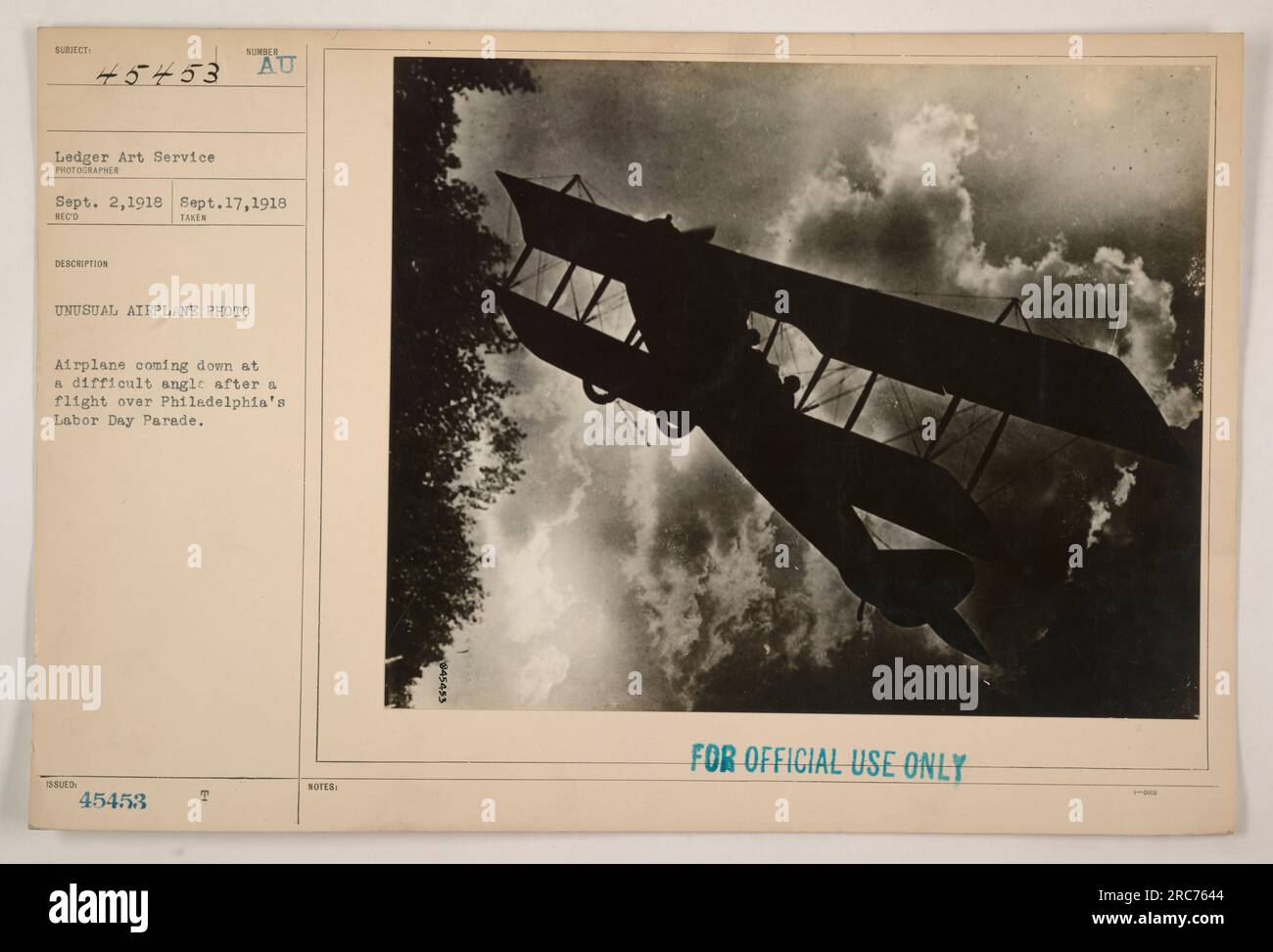 An airplane comes down at a difficult angle after a flight over Philadelphia's Labor Day Parade in September 1918. This image is labeled as 'unusual' and comes from the Ledger Art Service. It was taken between September 2, 1918 and September 17, 1918. The photo includes a number (45453) and a note indicating that it is for official use only. Stock Photo