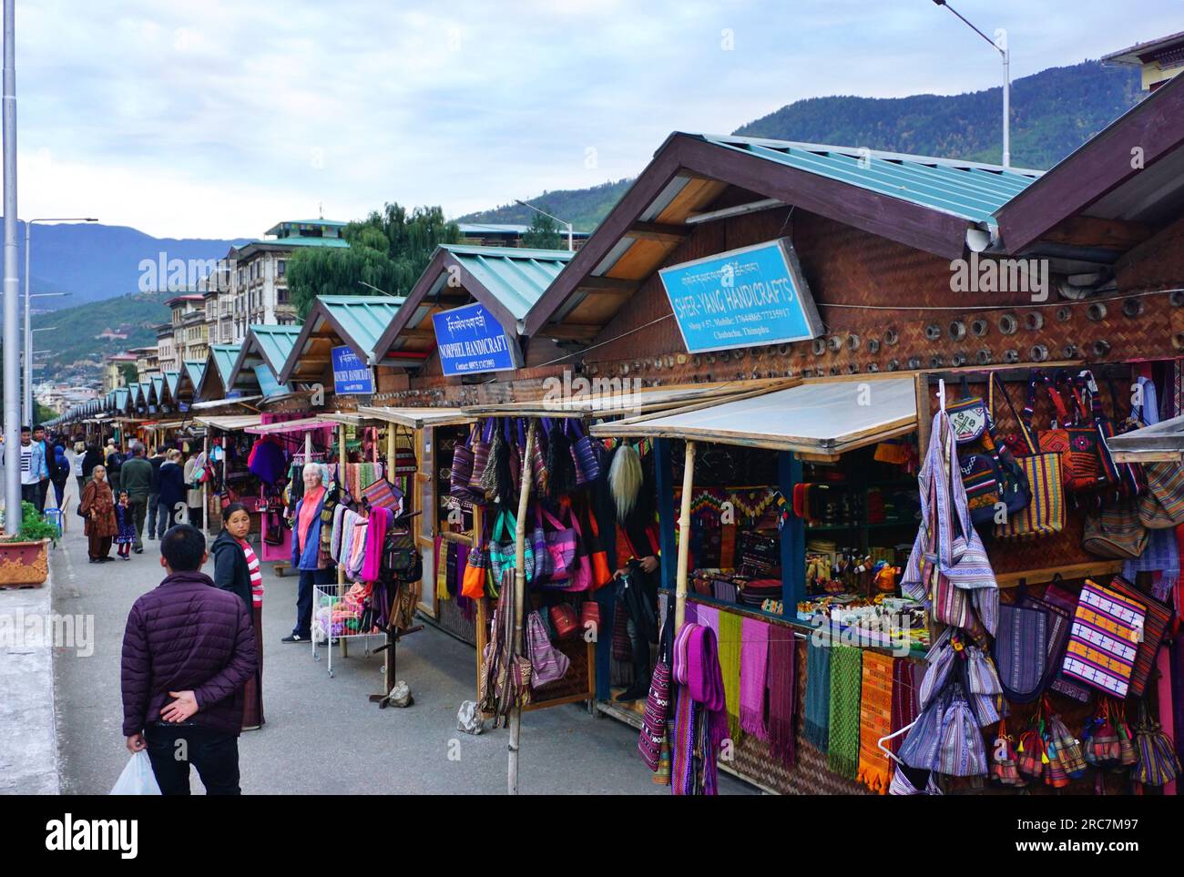 A row of identical shopping kiosks line a busy street in Thimphu, Bhutan. Local vendors sell clothing, jewelry, handicrafts, souvenirs and other items Stock Photo