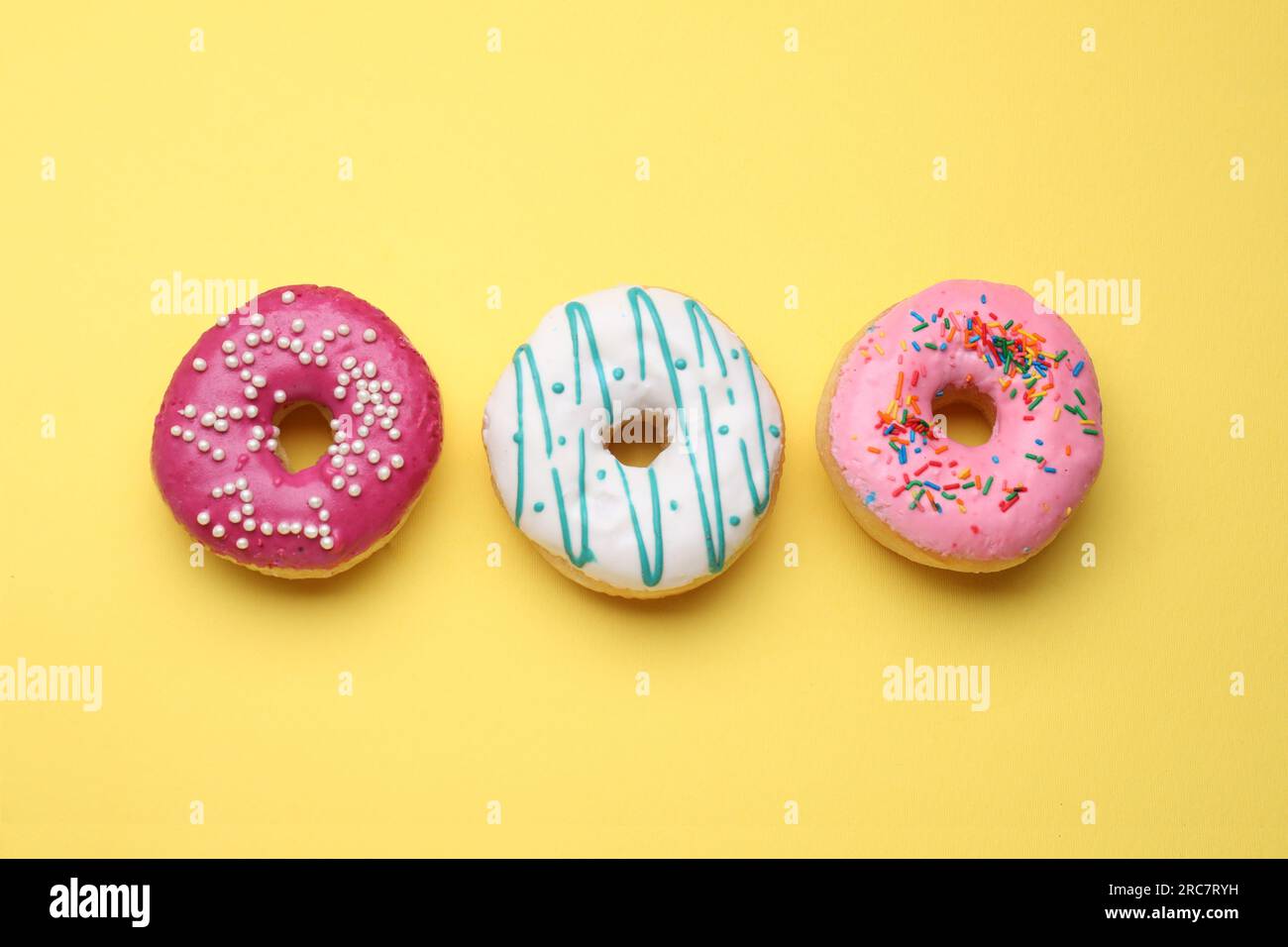 Tasty glazed donuts on yellow background, flat lay Stock Photo