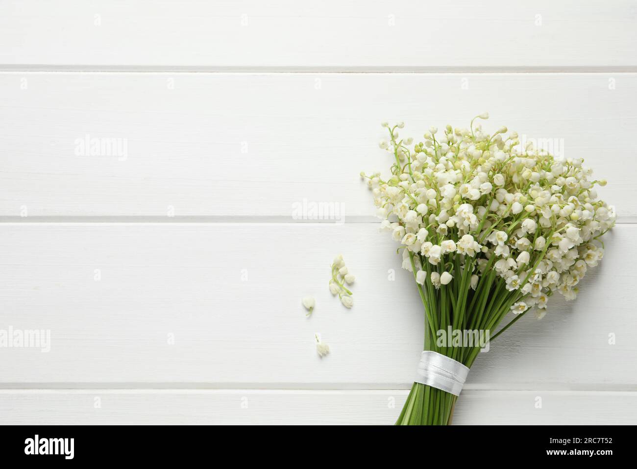 Beautiful lily of the valley bouquet on white wooden table, top view ...