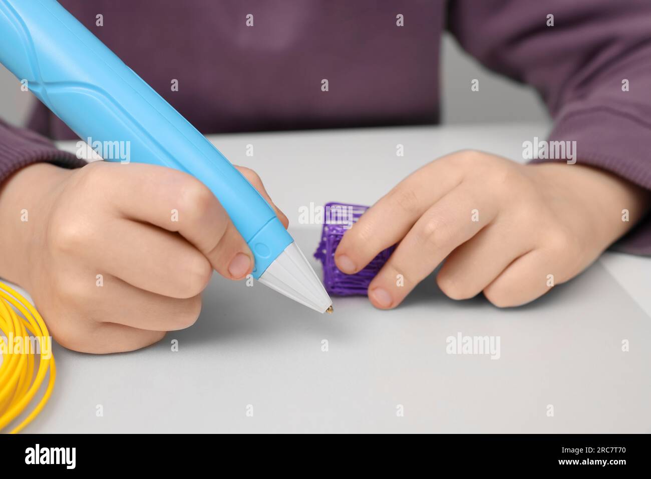 Boy drawing with stylish 3D pen at white table, closeup Stock Photo