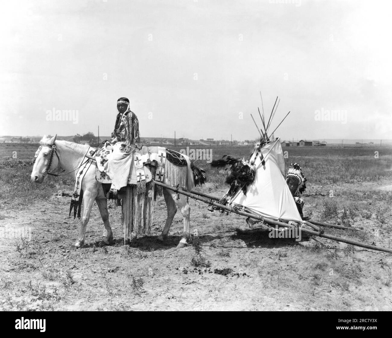 Montana:  1926. A Flathead Native American pulls her children on a travois on her way to the settlement in Montana where they will depart for the Chicago Rodeo.There they will pitch their camp in Grant Park and the  braves and squaws wil engage in tribal contests of skill and horsemanship. Stock Photo