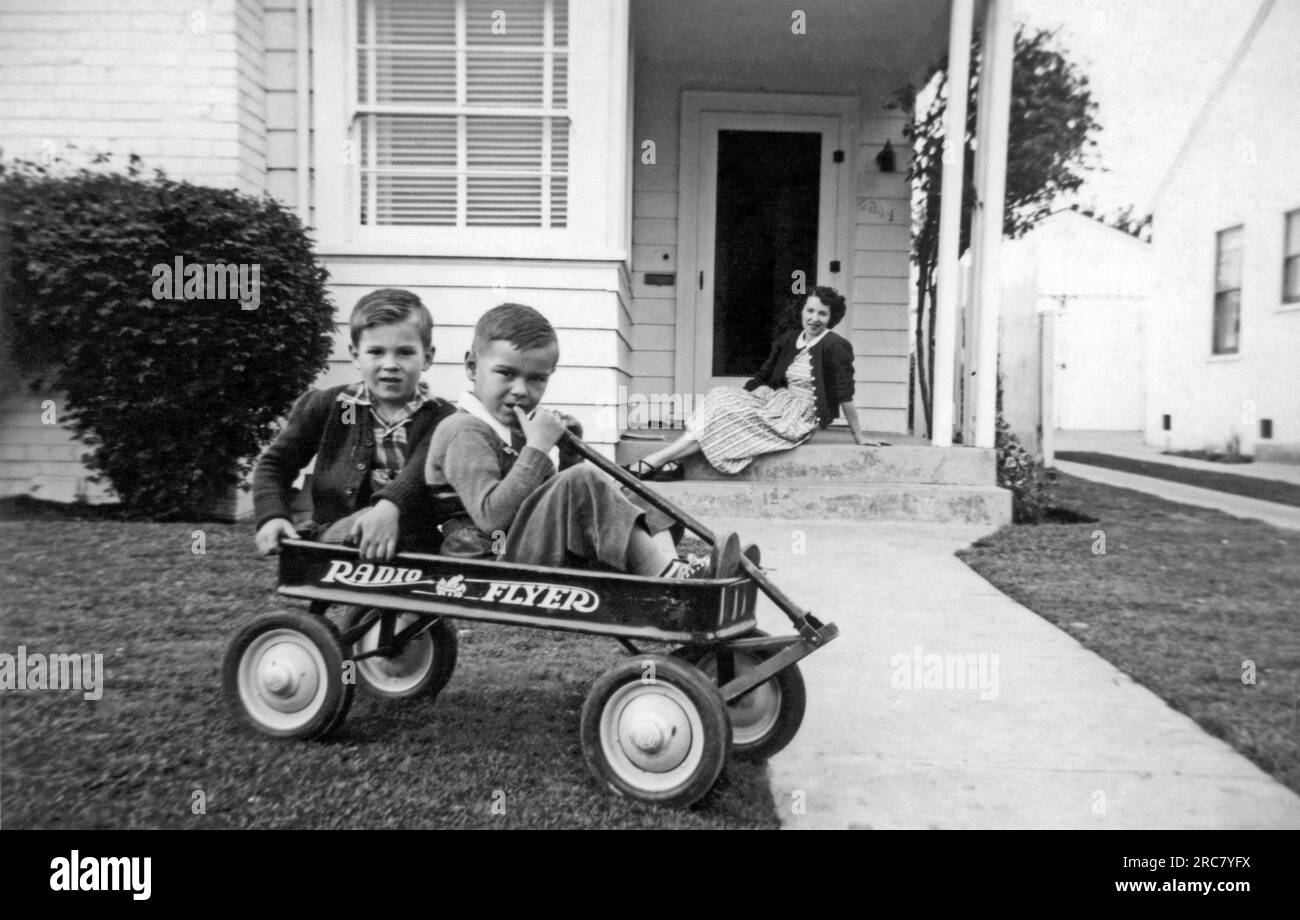 United States c. 1951. Two brothers sitting in their new Radio Flyer wagon while their mother