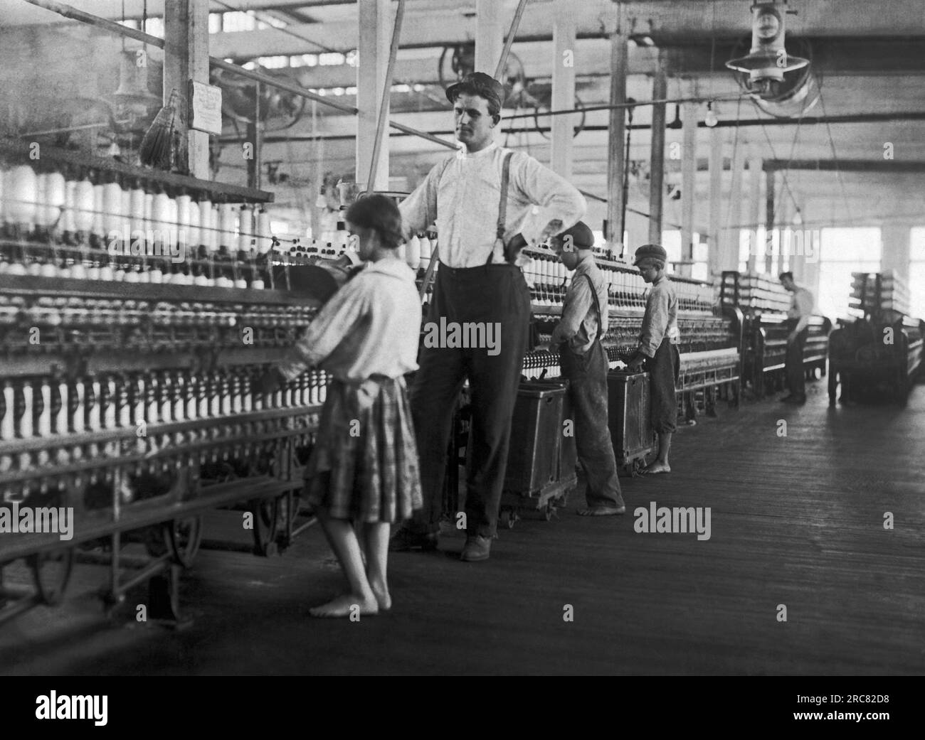 Yazoo City, Mississippi:  May 1911 A young spinner being watched by the overseer at Yazoo City Yarn Mills. Stock Photo