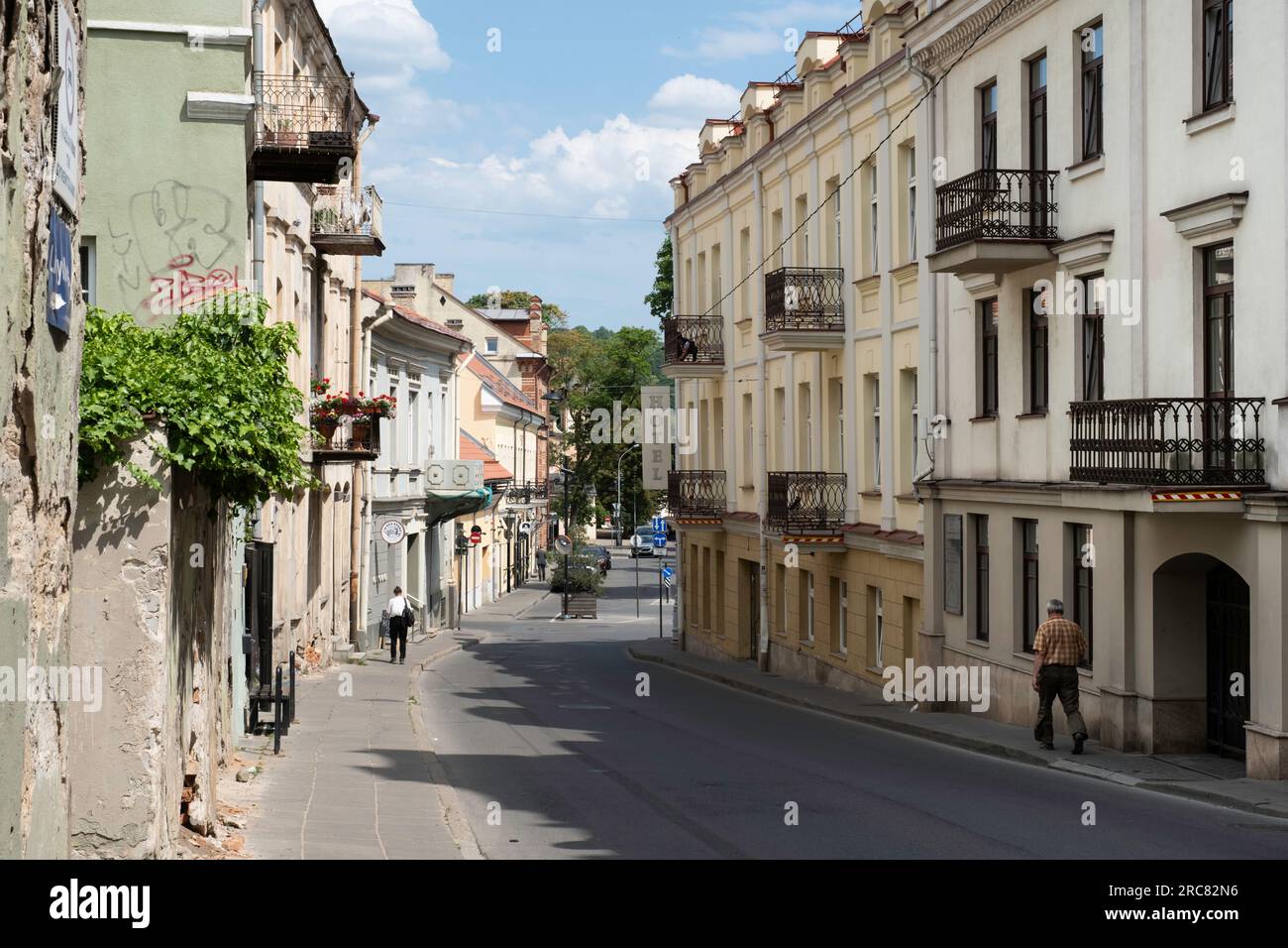 Descending street in Vilnius with facades of old historical buildings in pastel shades, many with balconies Stock Photo