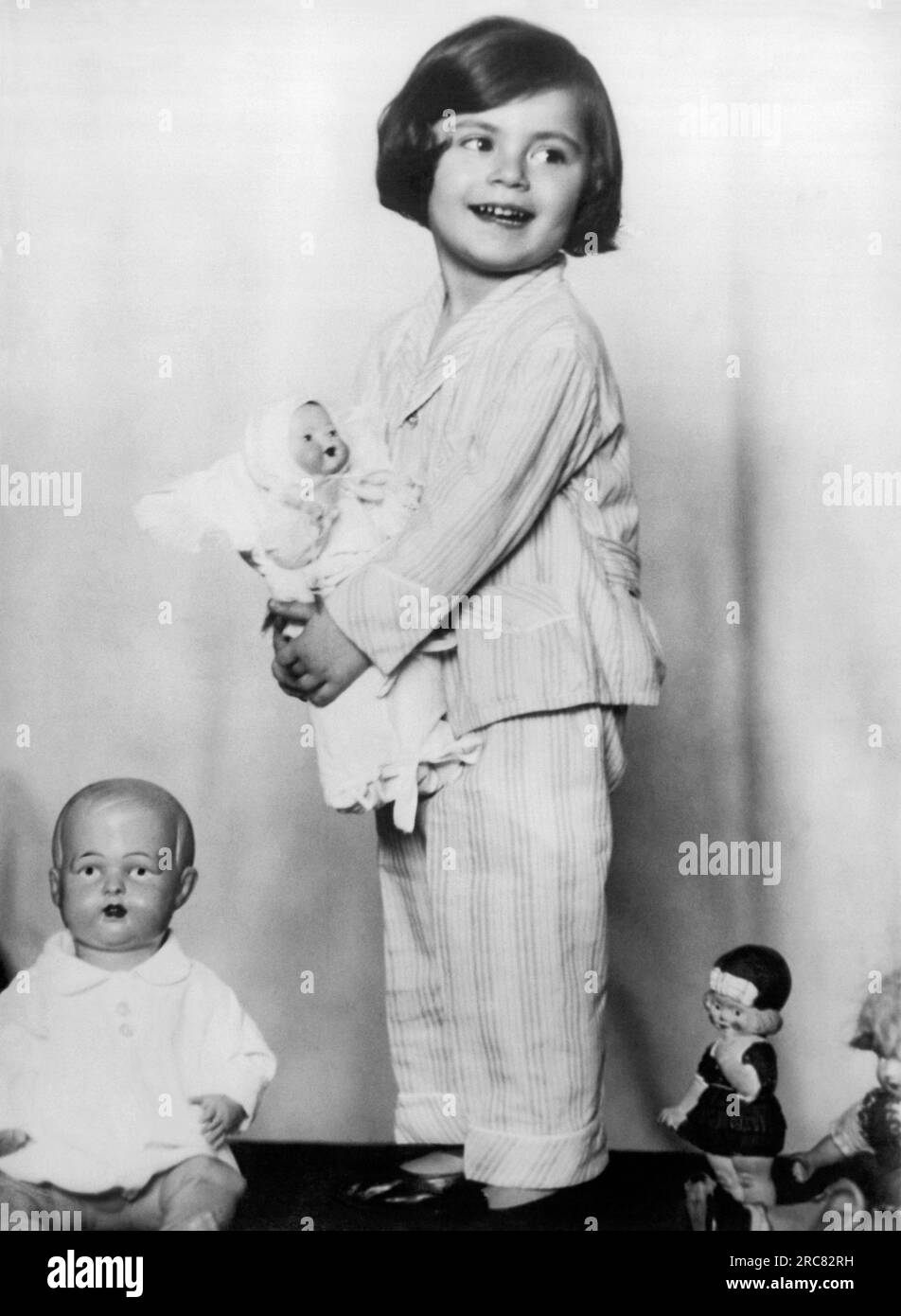 Rome, Italy:  June, 1930 Little Baroness Anna Soragno holds a doll presented to her by the Crown Princess of Italy. At left is a doll from the Crown Princess of Belgium, at the far right is one from the Crown Princess of Norway, and the doll standing in the middle is a gift from Princess Ingrid of Sweden. Stock Photo