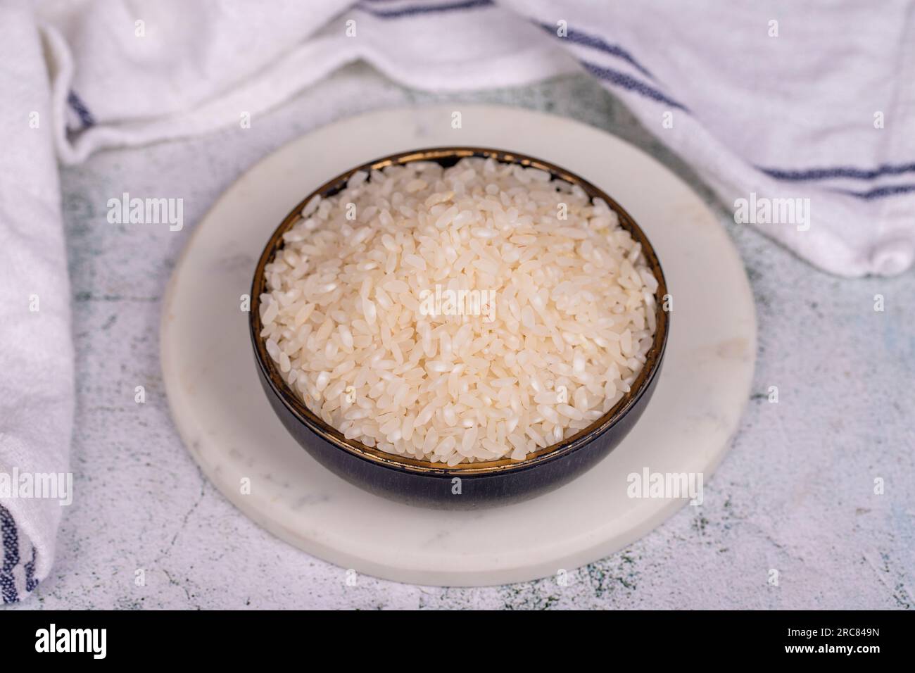Rice on stone background. Uncooked dry rice in bowl Stock Photo - Alamy