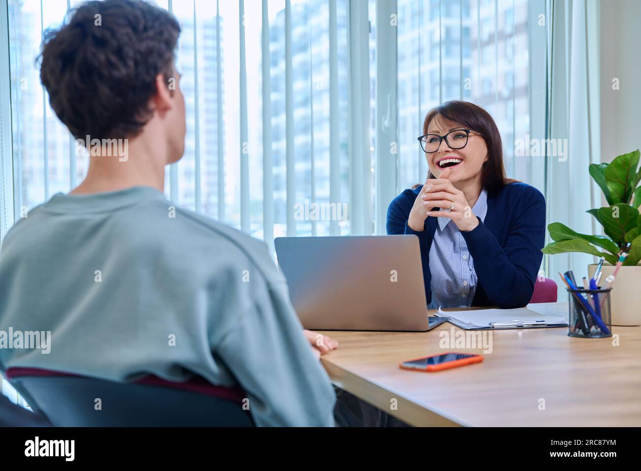 School psychologist supporting guy student, sitting in office of educational building Stock Photo