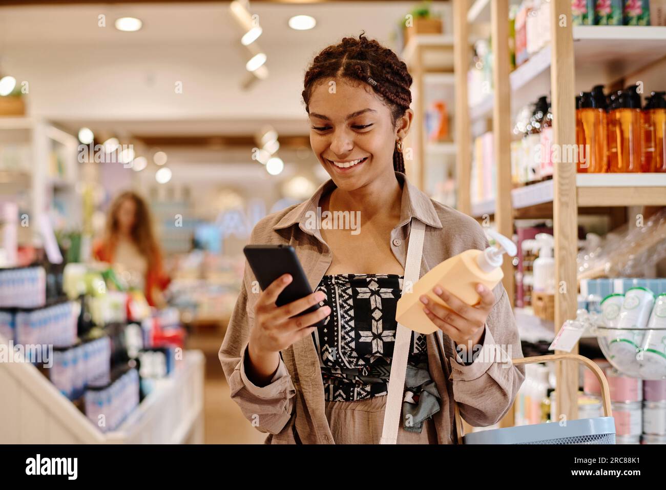 Young smiling customer using smartphone to buy cosmetics in shopping ...