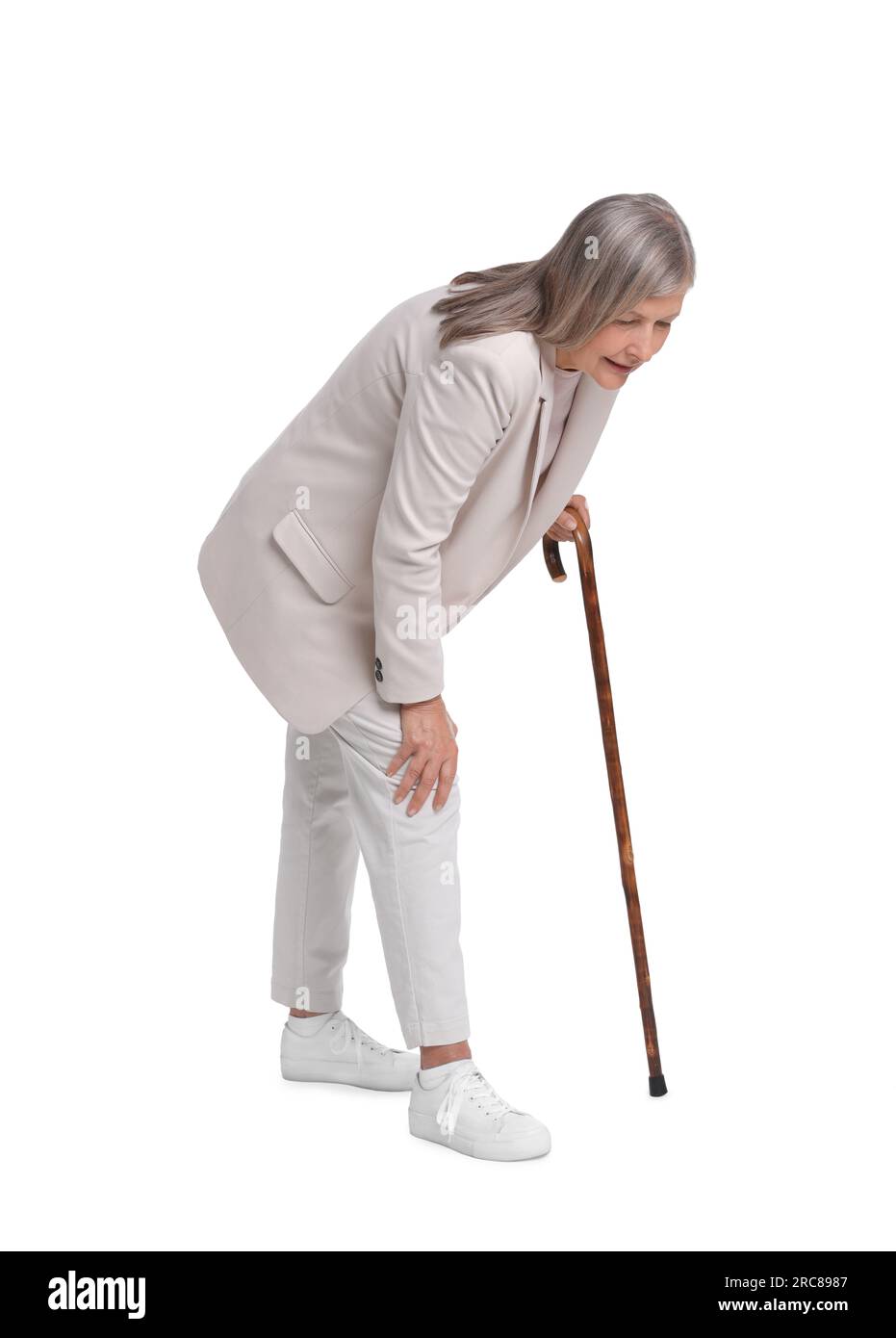Senior woman with walking cane suffering from knee pain on white
