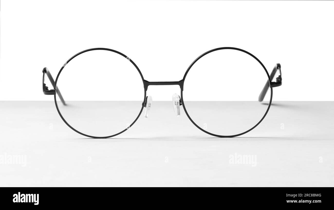 Round glasses with metal frame on table against white background Stock ...