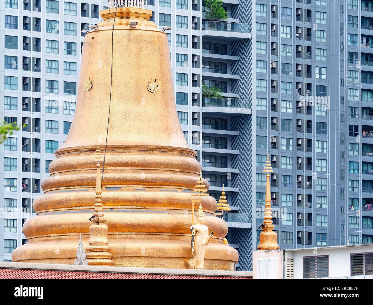 Traditional golden pagoda at a Buddhist temple in Thailand in front of a high rise, modern condominium located in Bang Na on the outskirts of Bangkok. Stock Photo
