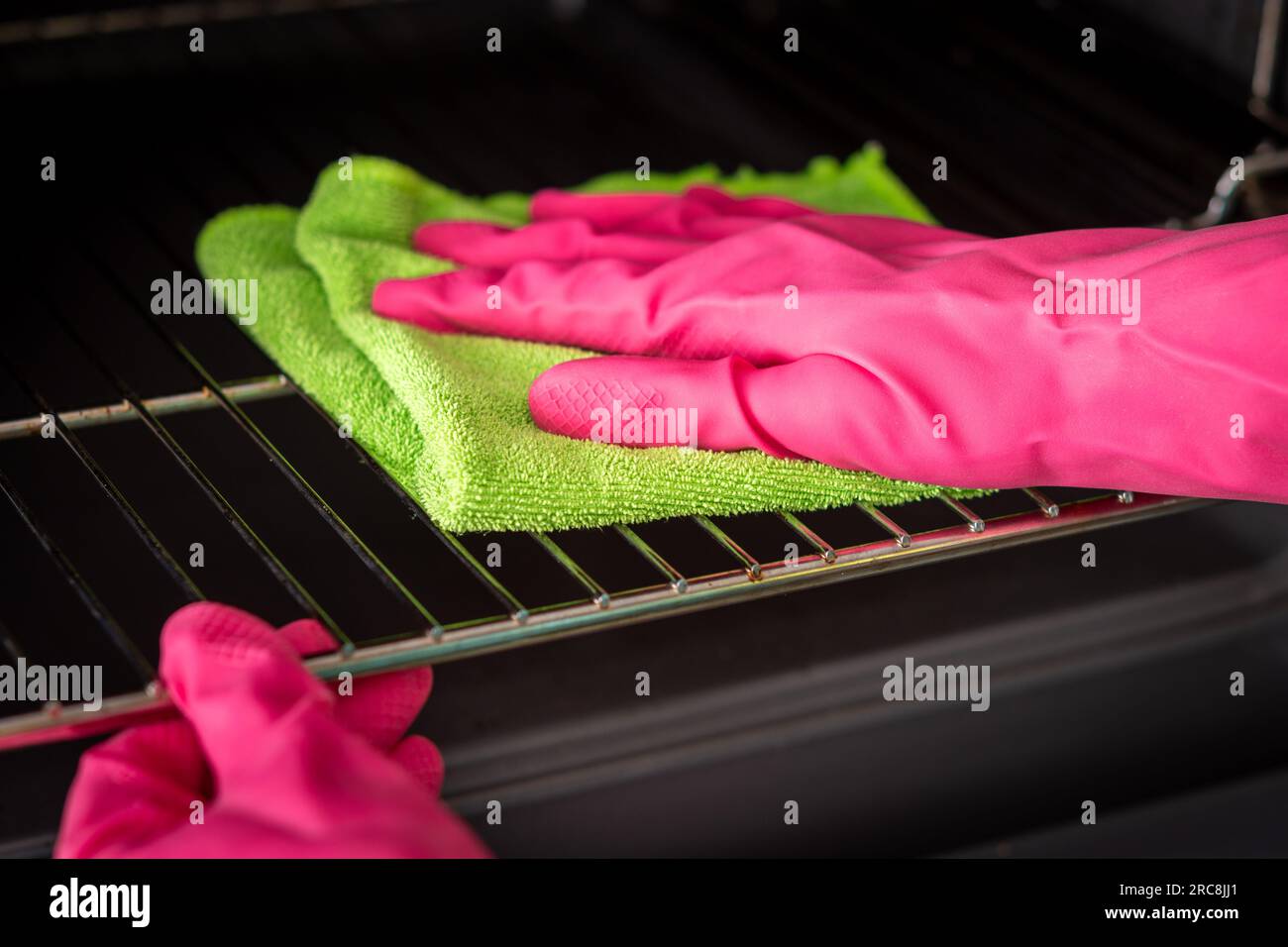 Cleaning the oven. Woman's hand in pink gloves cleans oven inside