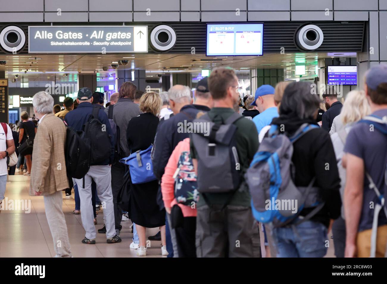 Hamburg, Germany. 13th July, 2023. Travelers stand in queues at the security checkpoint at Hamburg Airport. Hamburg Airport expects up to 350,000 passengers a week at the start of the vacation season. Credit: Bodo Marks/Bodo Marks/dpa/Alamy Live News Stock Photo