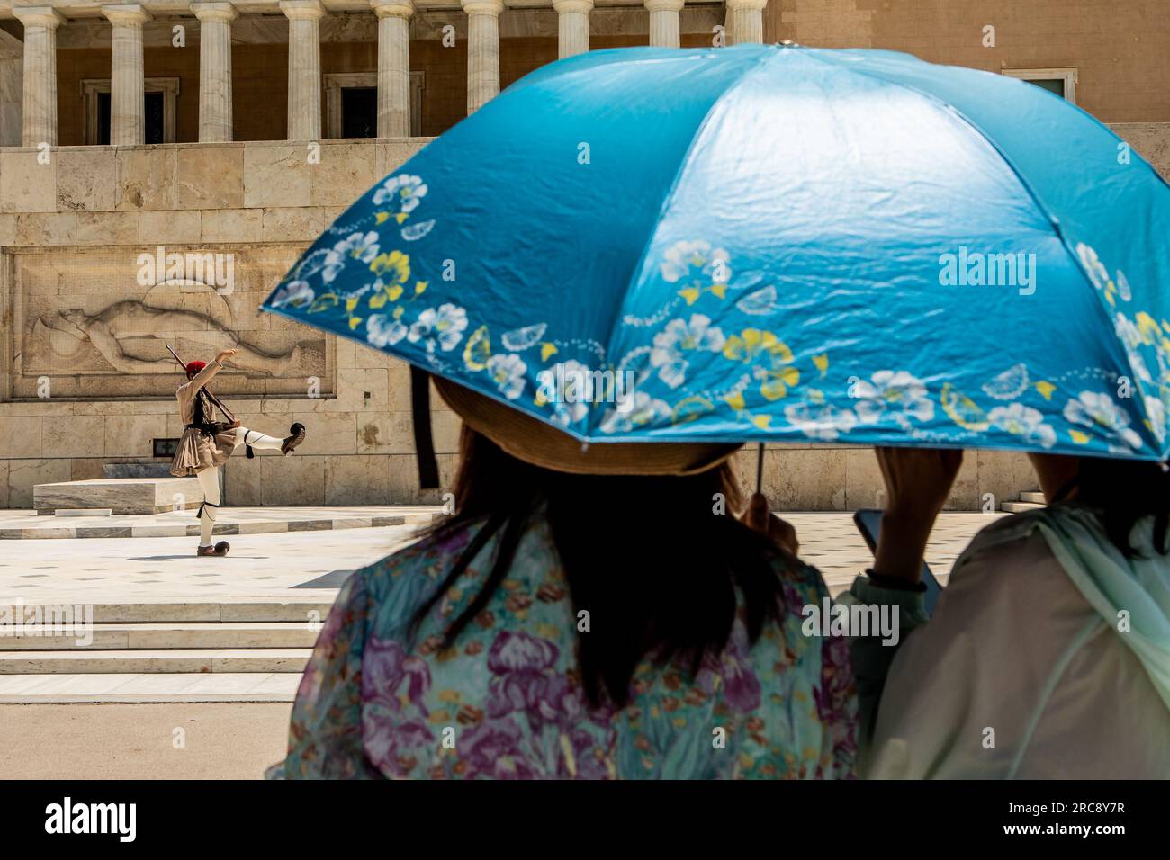 Athens, Greece. 12th July, 2023. People shelter from the sun under an umbrella in Athens, Greece, July 12, 2023. Credit: Panagiotis Moschandreou/Xinhua/Alamy Live News Stock Photo
