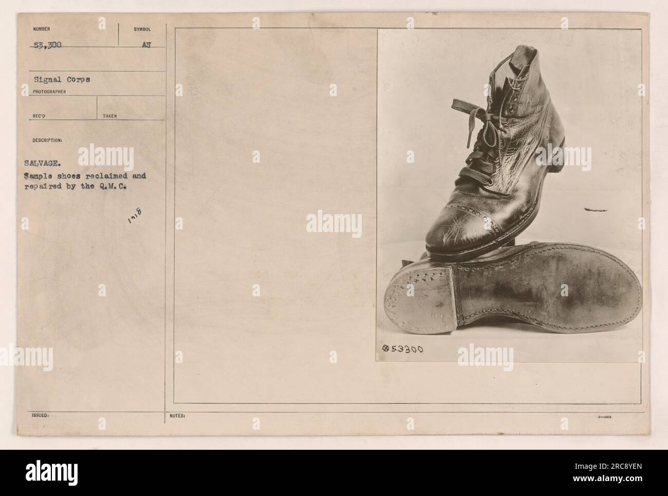Sample shoes salvaged and repaired by the Quartermaster Corps (Q.M.C.) with the identification number 53,300. The photograph was taken in 1890 and is labeled as a symbol of salvage. The shoes were reclaimed by the Signal Corps photographer to document military activities during World War One. Stock Photo