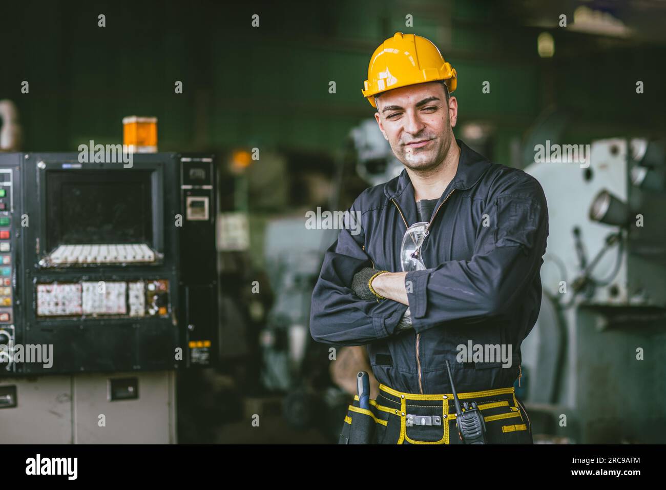 portrait engineer male technician expert skillful senior staff worker confident standing arm crossed with machinery factory Stock Photo
