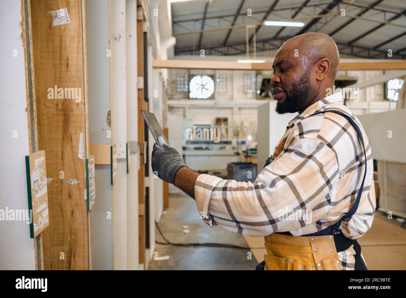 staff male black worker working in wood furniture industry factory checking selecting plywood wooden board type material in stock warehouse. Stock Photo