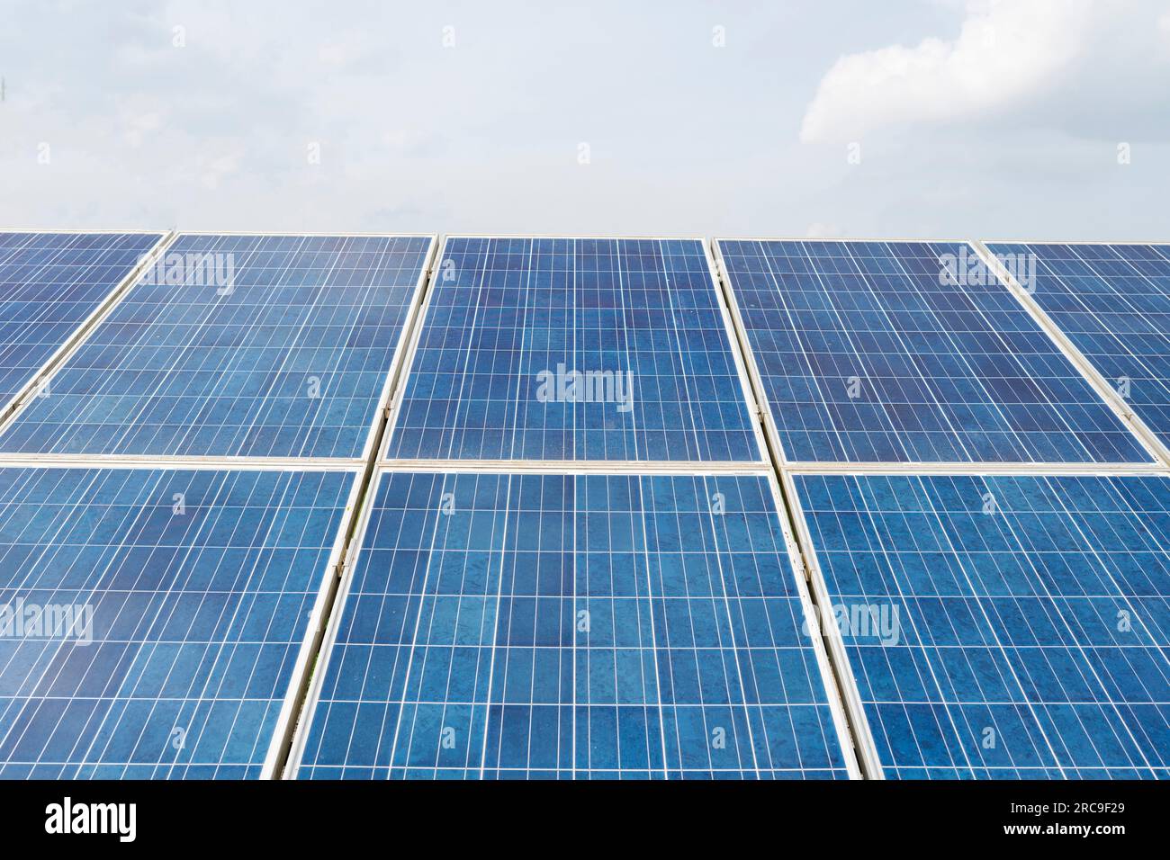 A bank of large solar panels as part of a solar farm on farm land in